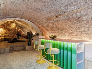 Eine Bar mit Backsteinwand, grünem Tresen und gelben Barhocker.