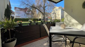 Ein Balkon mit Tisch und Stühlen, Blumentöpfen und Blick auf Gebäude.