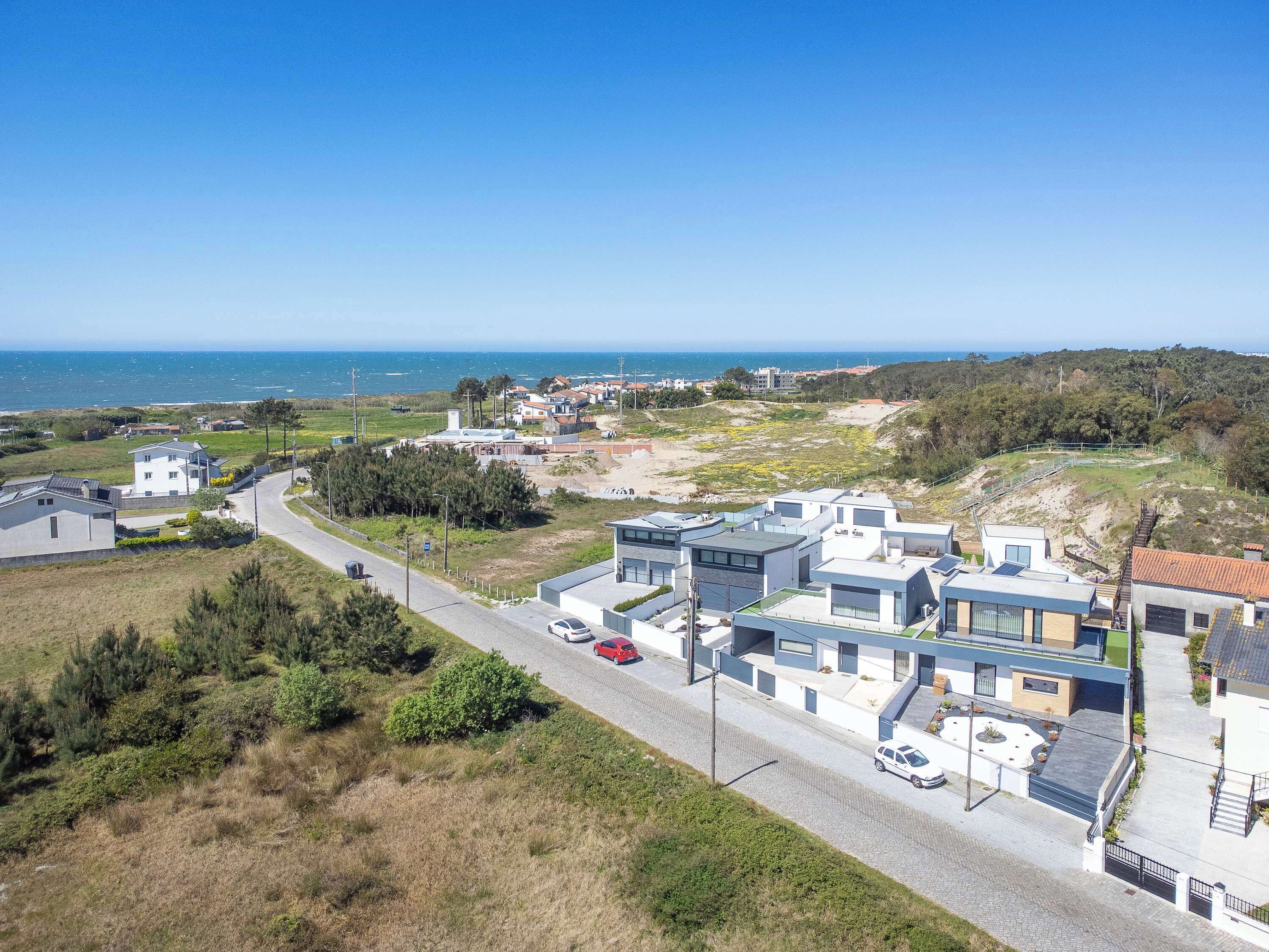 Un quartier résidentiel situé sur la côte, avec des maisons modernes, une route et une vue sur la mer.