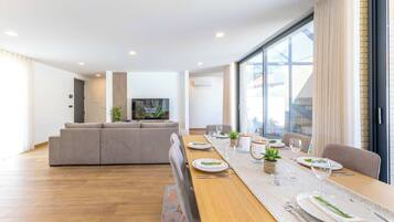 Una sala de estar moderna con un sofá, una mesa de comedor con platos y vasos, y un televisor en la pared.