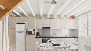 Cozinha compacta com geladeira, micro-ondas, cafeteira e mesa de jantar para dois.