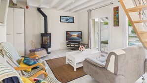 Uma sala de estar com lareira, sofá, mesa de centro e televisão.