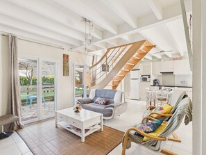 A spacious living area with a staircase, a dining area, and a kitchen. - House for 6, beach 400 m away, private garden (Batz-sur-Mer)