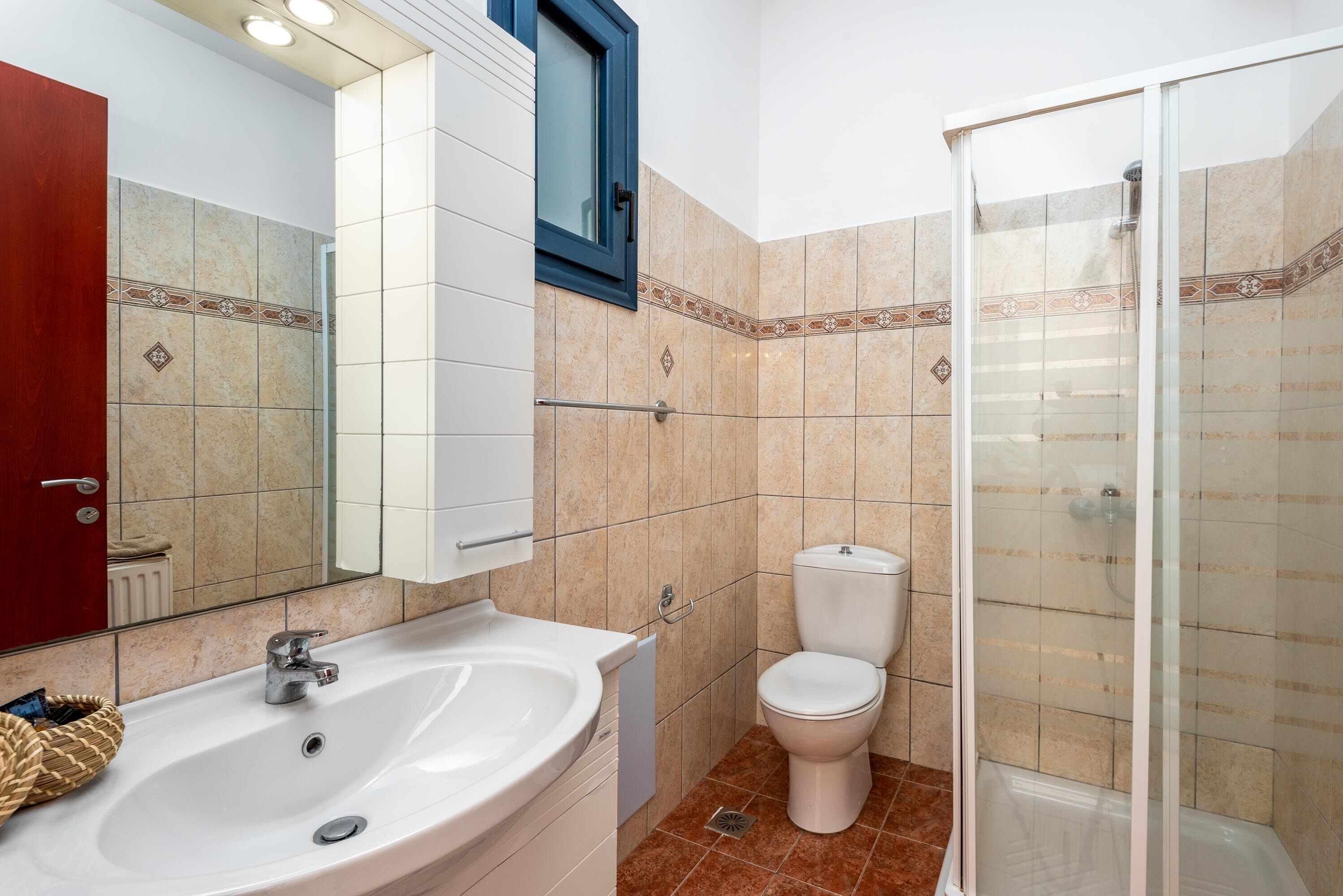 A bathroom with a sink, toilet, and glass-enclosed shower.