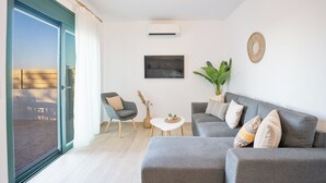 En moderne stue med en grå sofa, et lille sofabord, en stol og en potteplante.