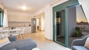 En moderne lejlighed med køkken, spiseområde og en balkon med planter.