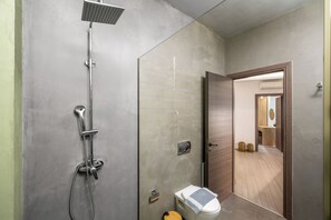 Ein modernes Badezimmer mit Dusche, Toilette und einer sichtbaren Tür zu einem anderen Raum.