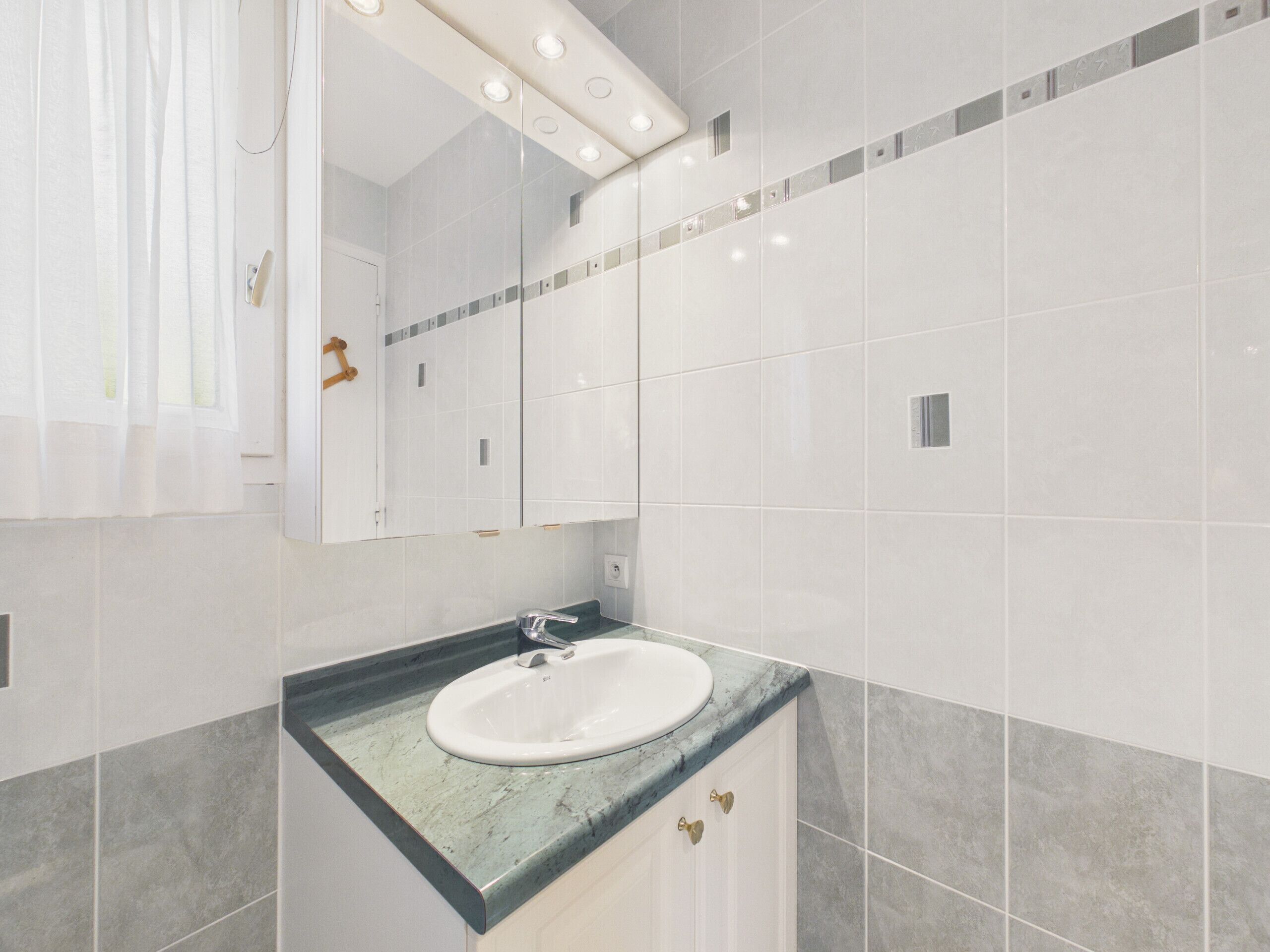 A bathroom with a white sink, a mirror, and a shower curtain.
