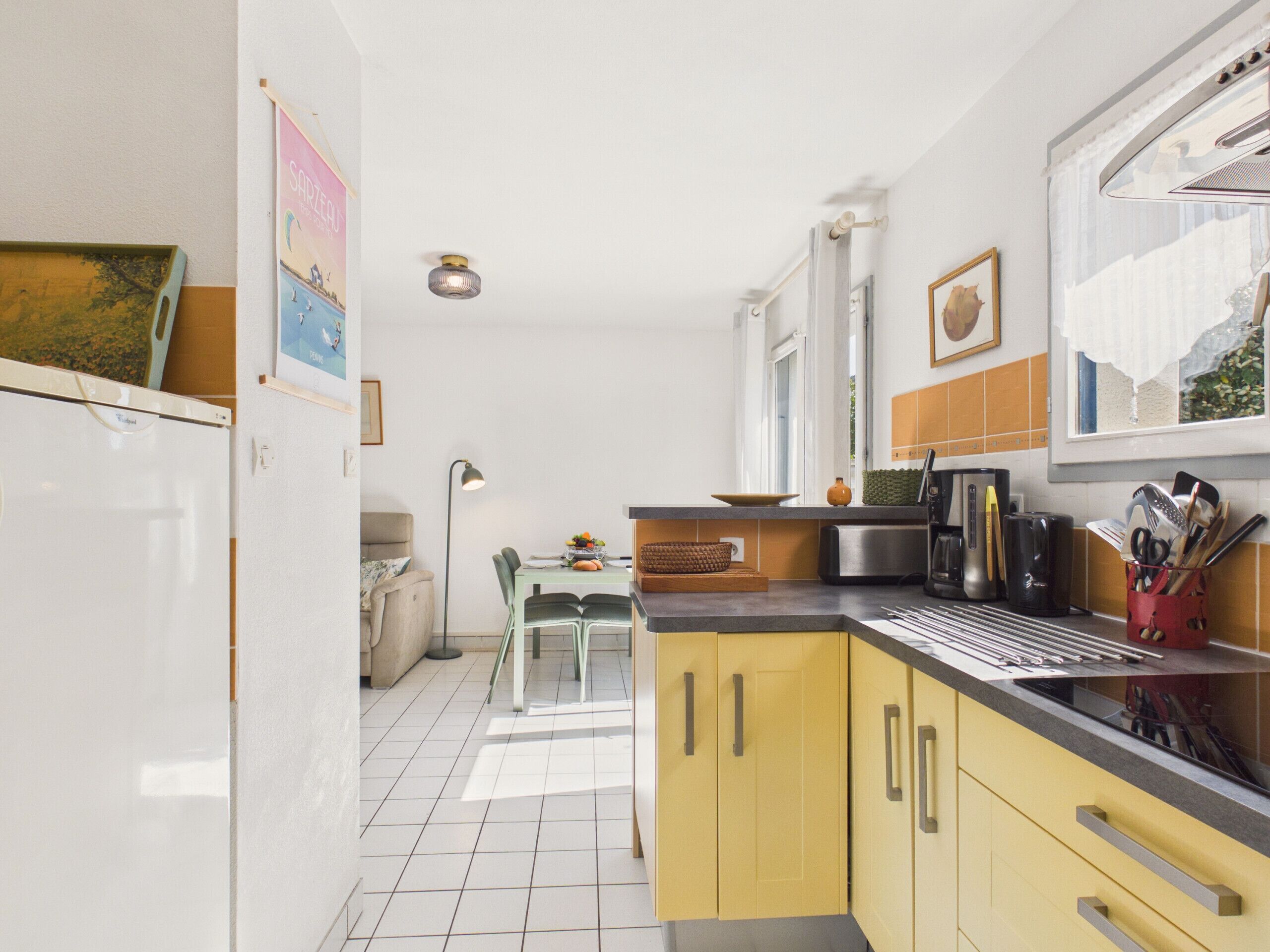 Una cocina compacta con gabinetes amarillos, una encimera negra y un comedor con mesa y sillas.
