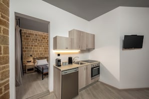 Eine kompakte Küche mit Geschirrspüler, Backofen und einem flachbildfernseher an der Wand.
