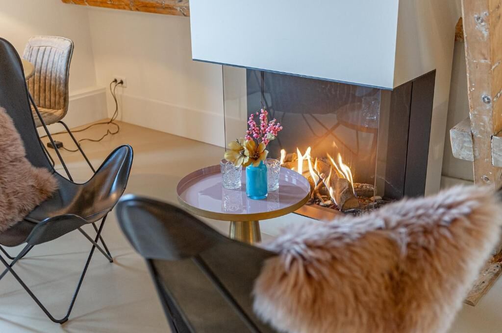 A cozy room with a fireplace, a round table with a vase, and two chairs.