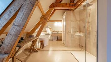 Un dormitorio tipo loft moderno con techo inclinado, cabina de ducha de vidrio y estructura de vigas de madera.