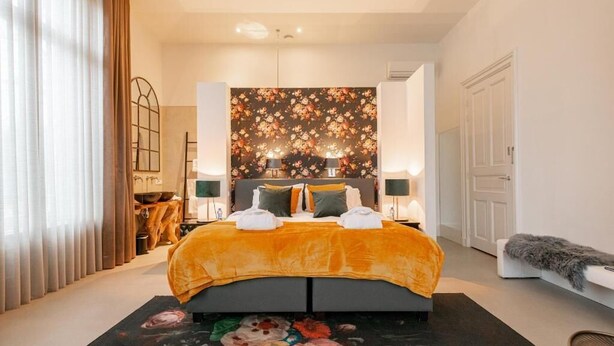 Un dormitorio moderno con una cama grande, un tapiz floral y vistas a un comedor.