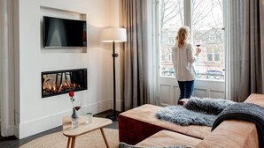 Una sala de estar moderna con chimenea, un televisor de pantalla plana y un ventanal con vista a la ciudad.