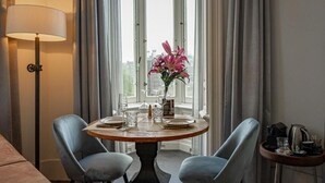 Un comedor con una mesa redonda preparada para dos personas, un florero y una lámpara.