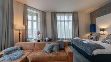 Habitación de hotel con sofá, cama, escritorio y vista a la ciudad.