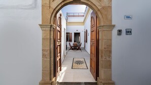 A hallway with a wooden door frame, a dining area with a table and chairs, and a small balcony. - Villa Yannis in Lindos (Rhodes)