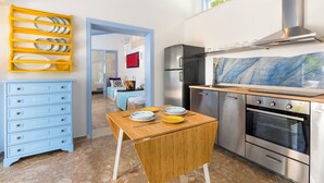 Una cucina moderna con un tavolo di legno, elettrodomestici in acciaio inossidabile e un espositore giallo per piatti.