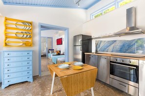 Eine moderne Küche mit Holztisch, Edelstahlgeräten und einem gelben Geschirrgestell.
