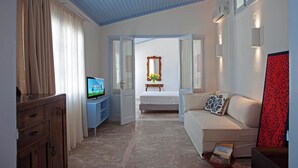 Una camera d'albergo con un letto, un divano, una televisione e un mobile in legno.