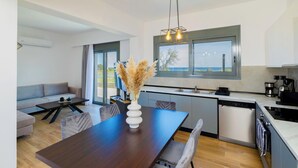 A modern kitchen with a dining area, a sofa, and a view of the outdoors.
