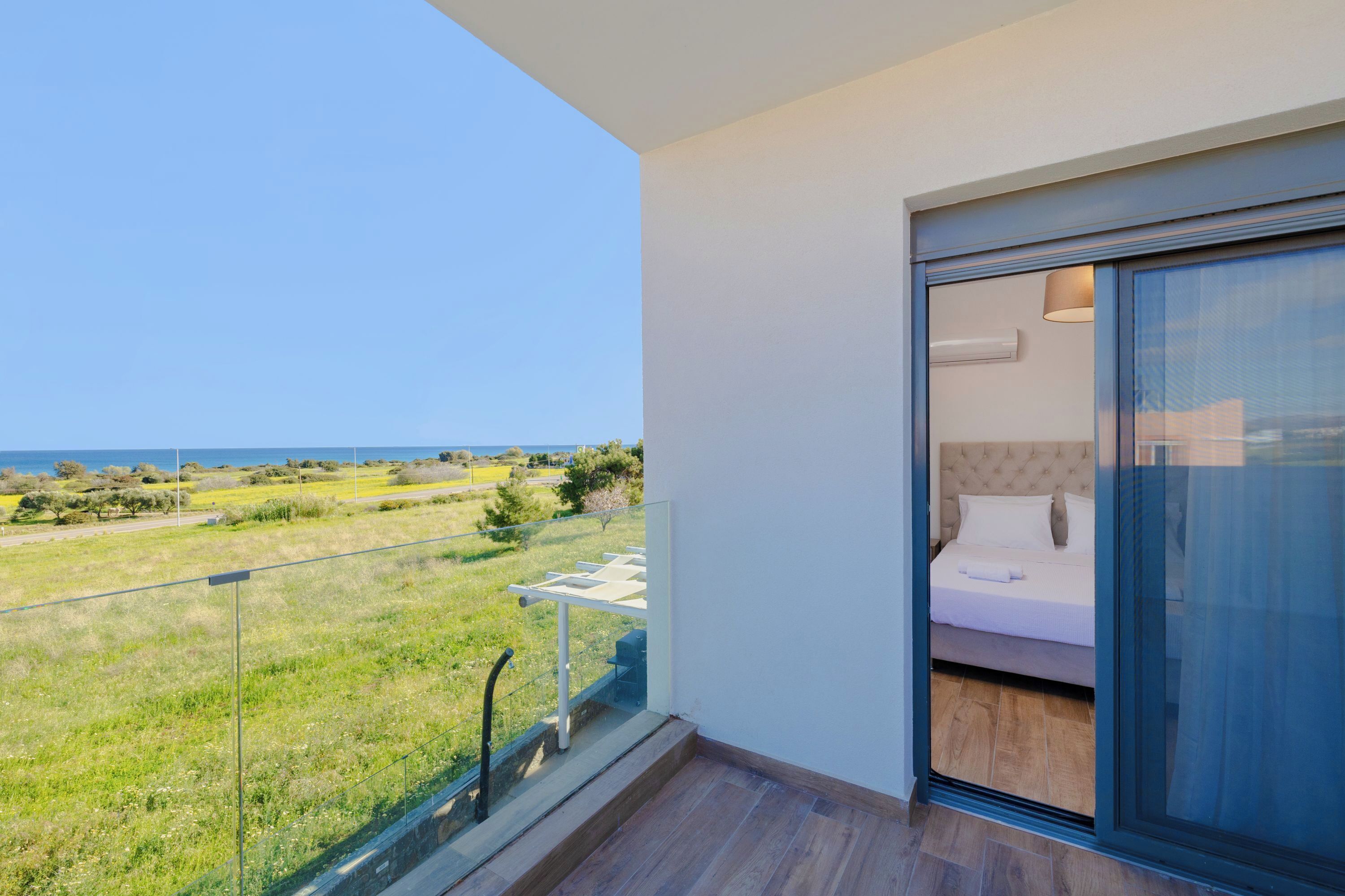 Een balkon met uitzicht op zee en een groene omgeving.