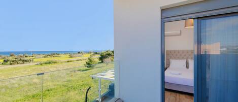 Een balkon met uitzicht op zee en een groene omgeving.