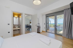 Une chambre d’hôtel moderne dotée d’un grand lit, d’une salle de bain avec un lavabo et un miroir, et d’un balcon offrant une vue agréable.