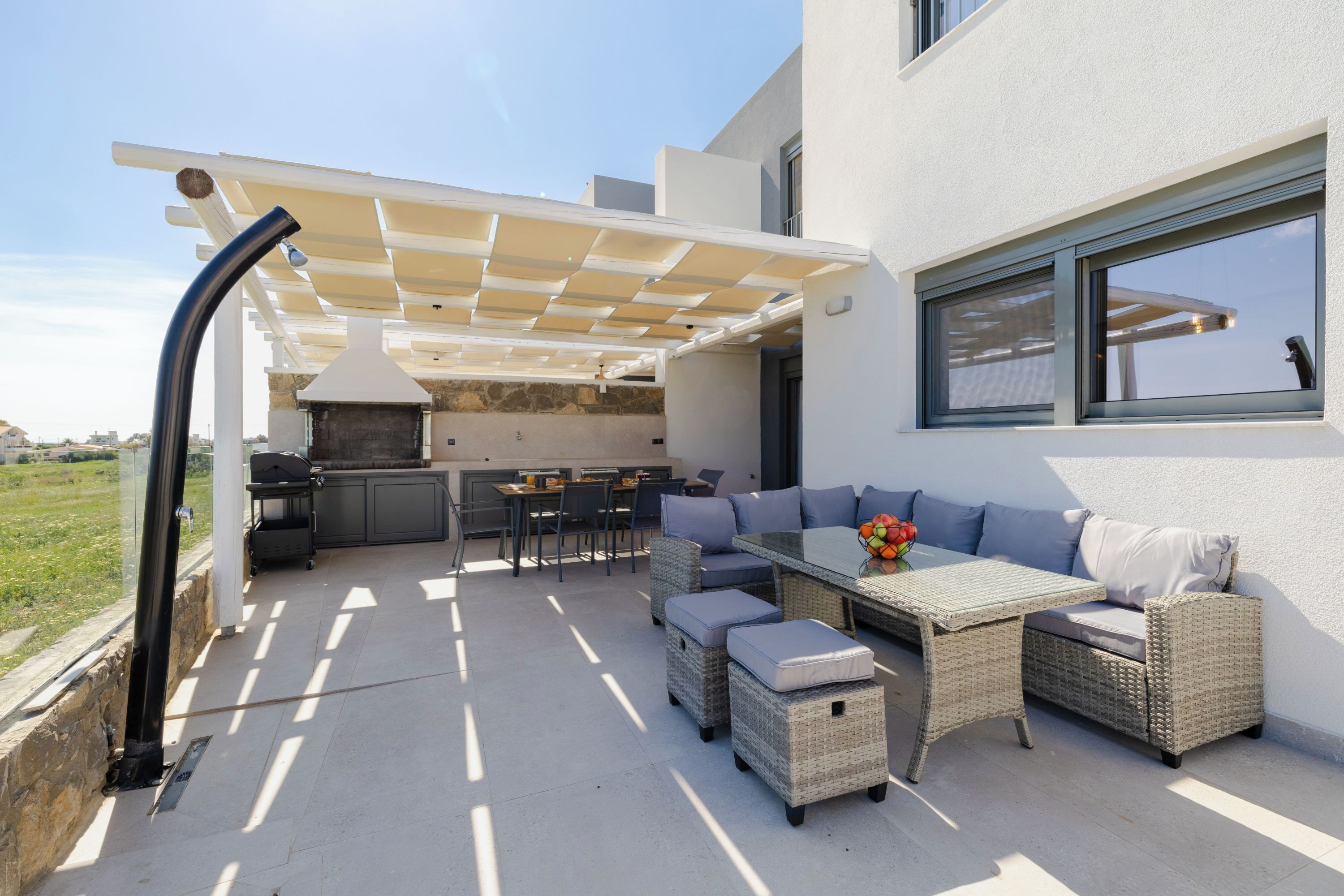 Un espace extérieur aménagé en terrasse, avec une table à manger, des meubles en osier et un barbecue.