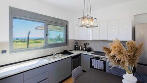 A modern kitchen with a large window, a built-in dishwasher, and a dining area with a table and chairs.