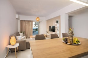 A modern living room with a sofa, a dining table with fruit, and a TV. - Sea Homes Villas - Villa Alberto (Rhodes)