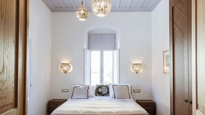 Een slaapkamer met een groot bed, houten vloeren en een raam met natuurlijk licht.