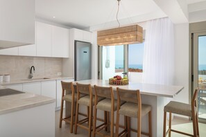 Eine moderne Küche mit einer zentralen Kochinsel, Barhocker und Meerblick.