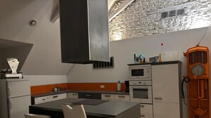 Eine moderne Küche mit einer zentralen Kochinsel, integrierten Geräten und einer Wand aus Stein.