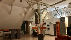 Eine moderne Küche mit einer Steinwand, einem Essbereich mit Tisch und Stühlen sowie einer großen Topfpflanze.