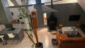 Eine moderne Küche mit Backofen, ein Essbereich mit einem weißen Stuhl und ein Wohnzimmer mit einer braunen Couch.