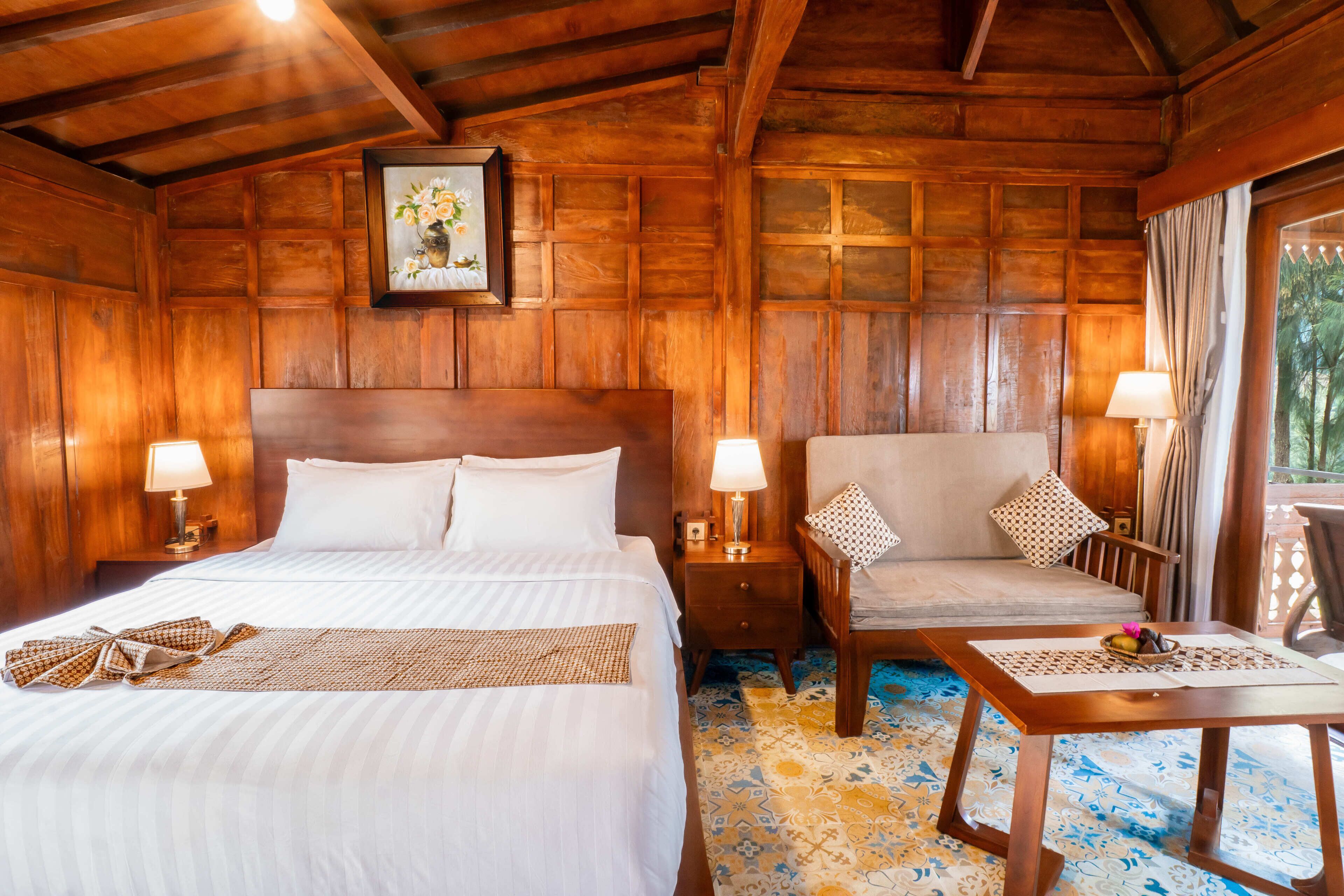 Una habitación con piso de madera, una cama, un sofá, una mesa y una mesita de noche.