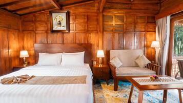 Una habitación con piso de madera, una cama, un sofá, una mesa y una mesita de noche.