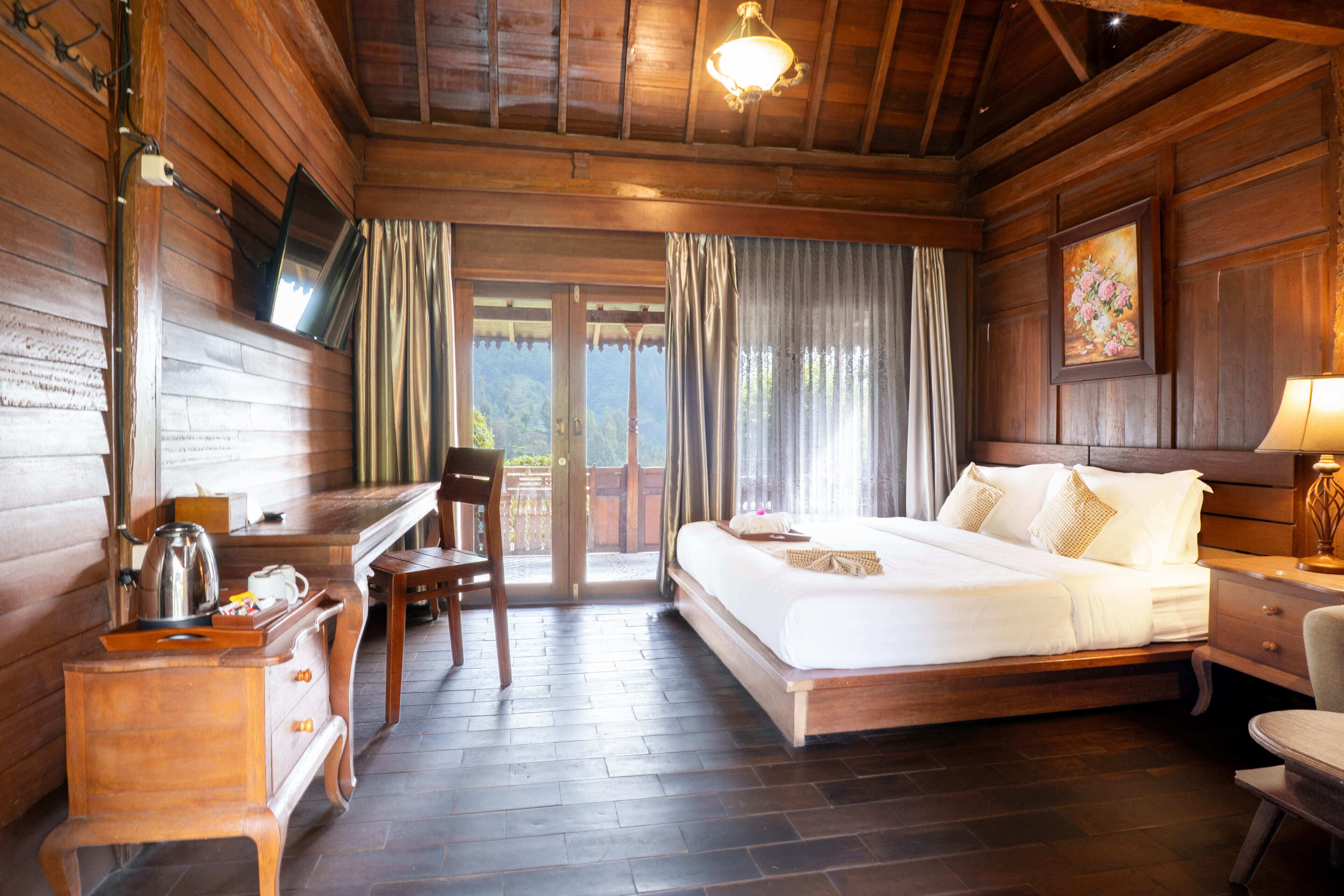 A wooden room with a bed, desk, chair, and a television on the wall.
