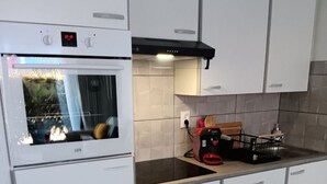 Ett kök med en inbyggd ugn, en köksfläkt och en bänkskiva med en brödrost och en vattenkokare.