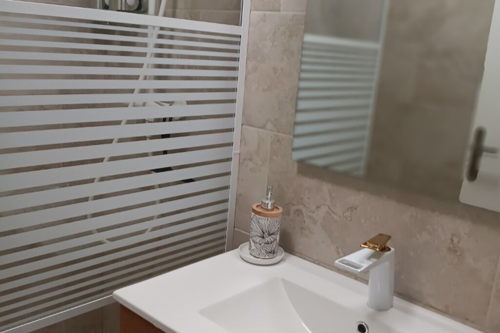 Ein Badezimmer mit einem weißen Waschbecken, einem dekorativen Seifenspender und einem Spiegel.