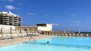 Une piscine avec des chaises longues et, au fond, un bâtiment portant l’inscription « Beach & Fitness Club ».