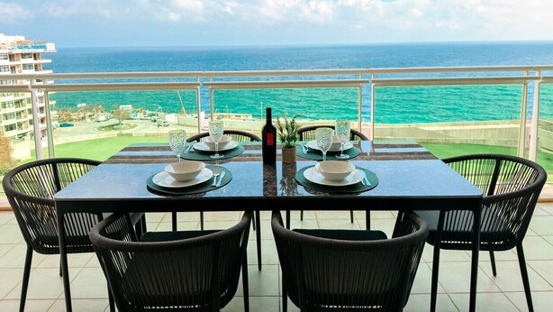 Une table à manger dressée pour quatre personnes, avec vue sur l’océan.