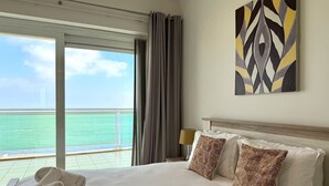 Une chambre d’hôtel avec un lit, des oreillers, un tableau et une vue sur l’océan.