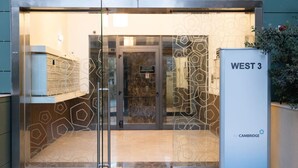 Une entrée moderne avec une porte en verre, une enseigne indiquant « WEST 3 » et une étiquette indiquant « pour CAMBRIDGE ».