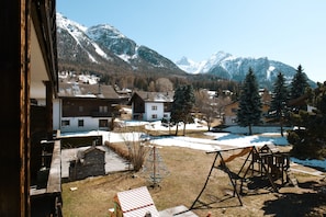 Ein Wohngebiet mit Häusern, einem Spielplatz und schneebedeckten Bergen im Hintergrund.
