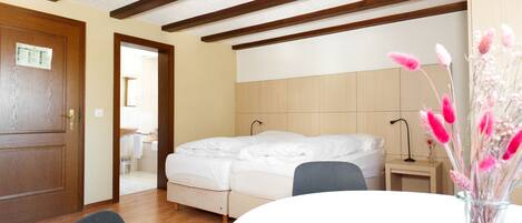 Un dormitorio con una cama, una mesita de noche, una silla y un florero con flores.