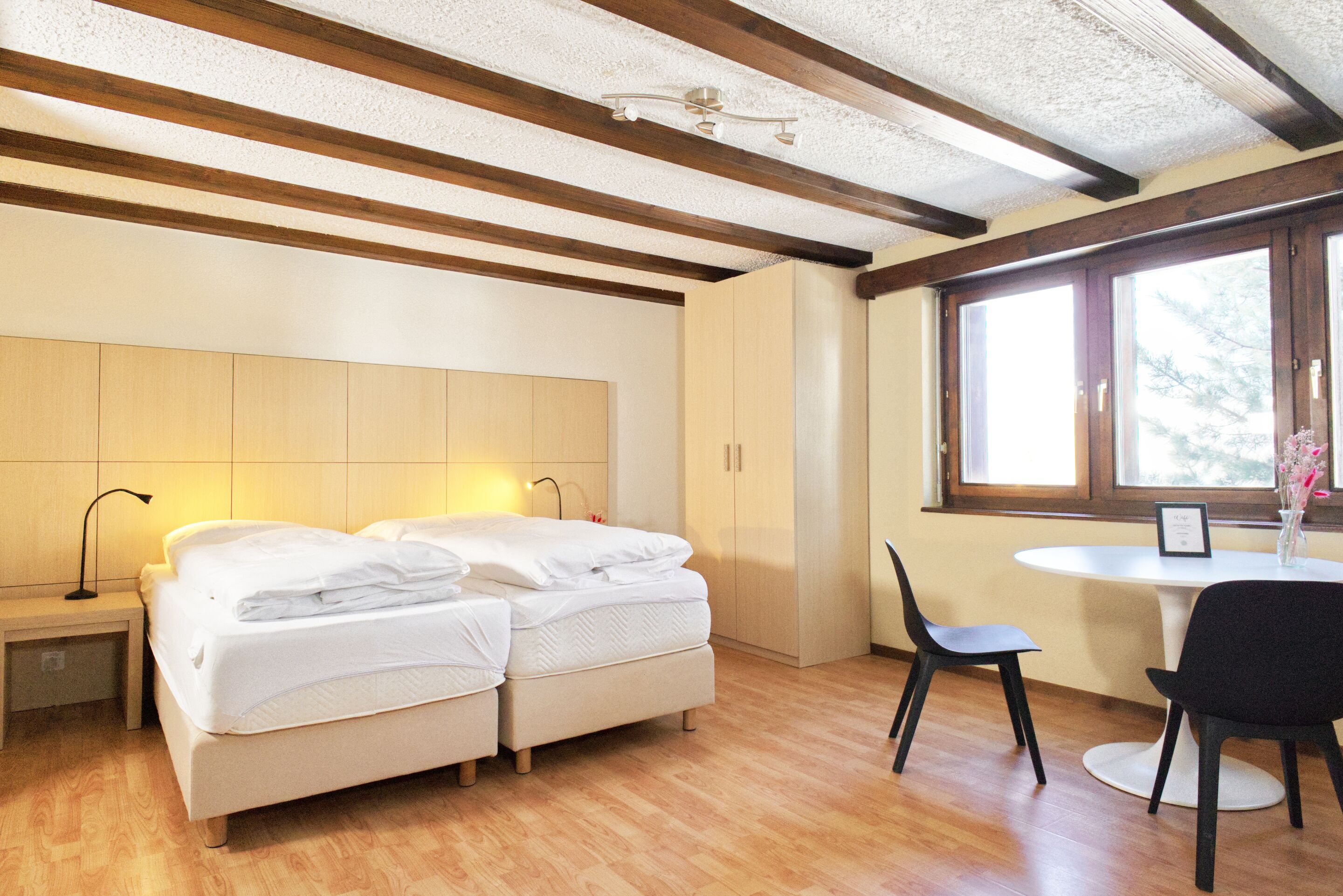 Une chambre avec un lit, une table de chevet, une lampe et une fenêtre donnant sur un beau paysage.