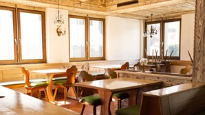 Un restaurante con muebles de madera, ventanas amplias y lámparas colgantes.