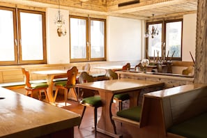 A restaurant with wooden furniture, large windows, and hanging light fixtures.